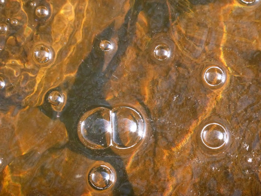 white bubbles orange ripples in stream