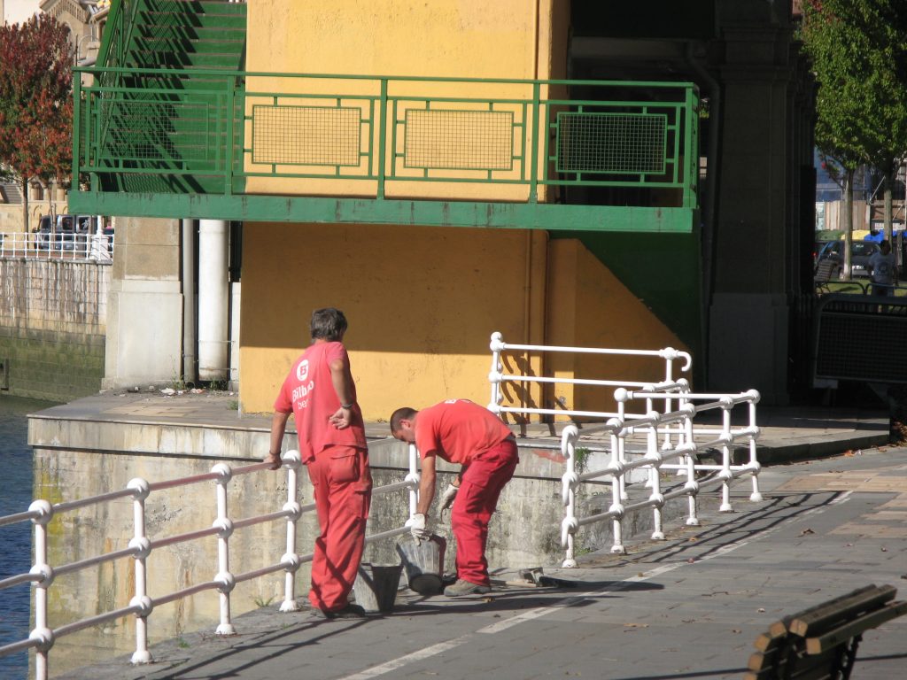 red-overalled workmen by bridge