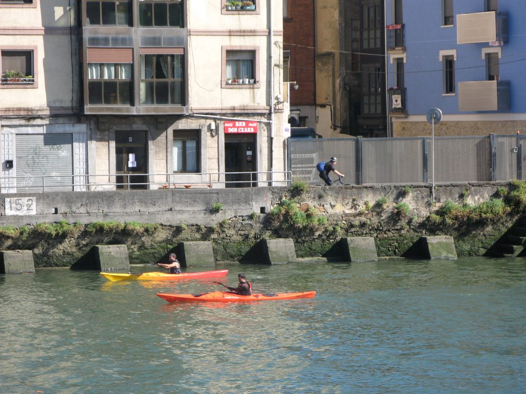canoes and cyclist on riverbank