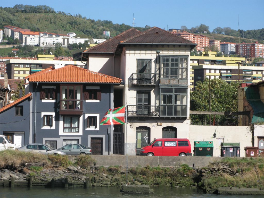 grey buildings with flag and red van