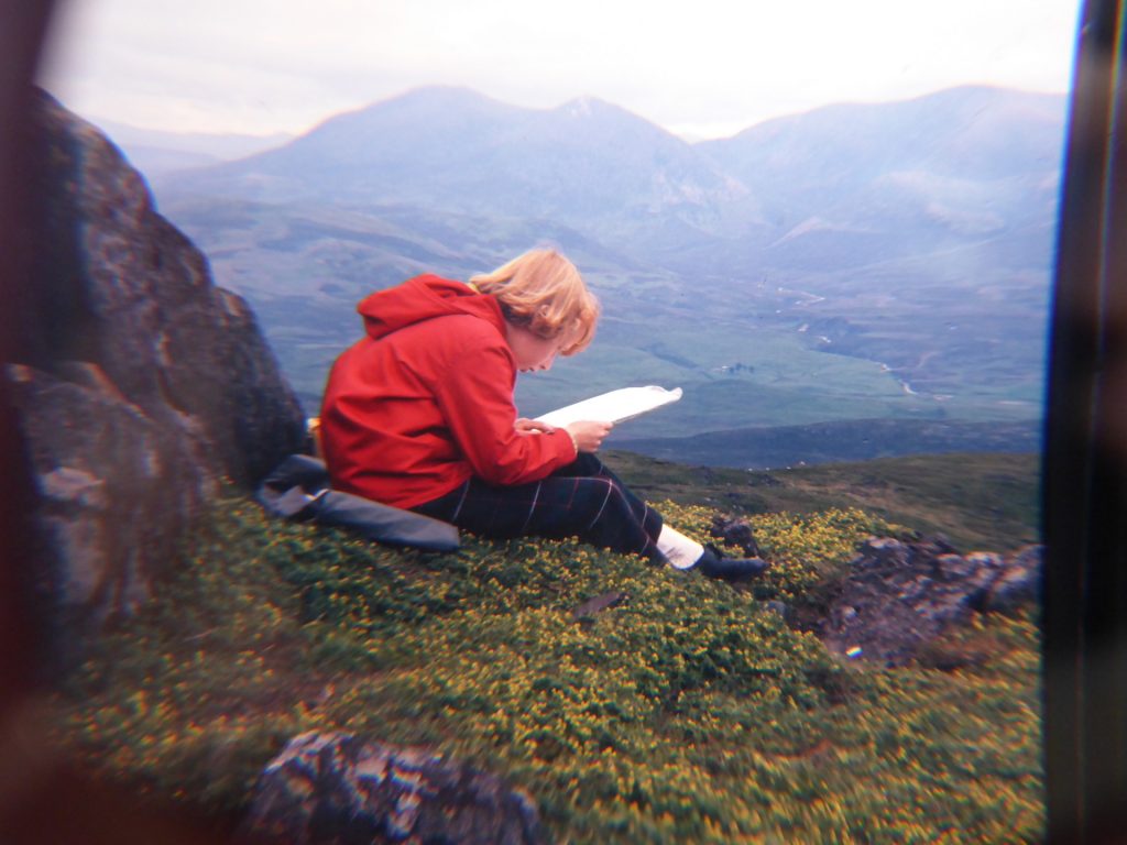 girl on hillside in red anorak reading map