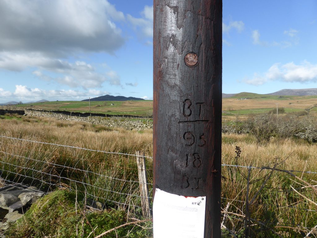 tarred BT post and view across to dark coloured hill