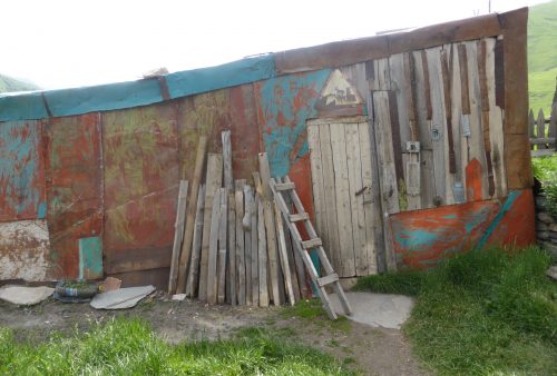wood stacked against rusty metal wall