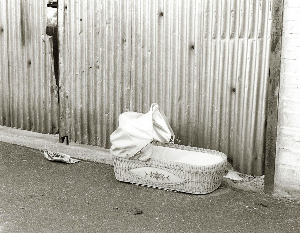 baby cot abandoned by corrugated fence