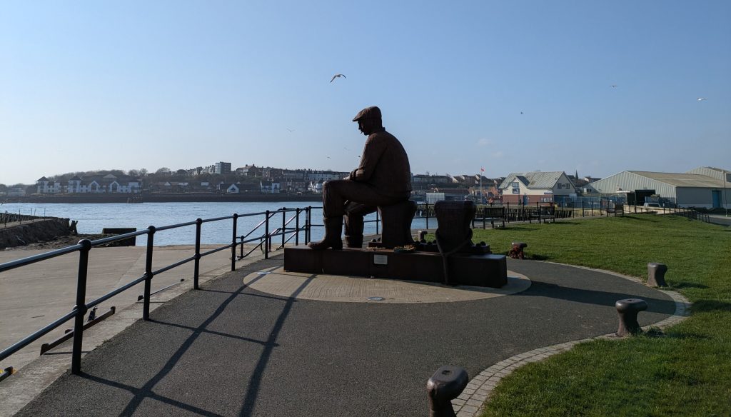 old man in flatcap sitting on the quay - statue